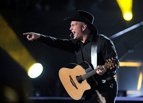 Garth Brooks pointing to the crow while playing his guitar on stage